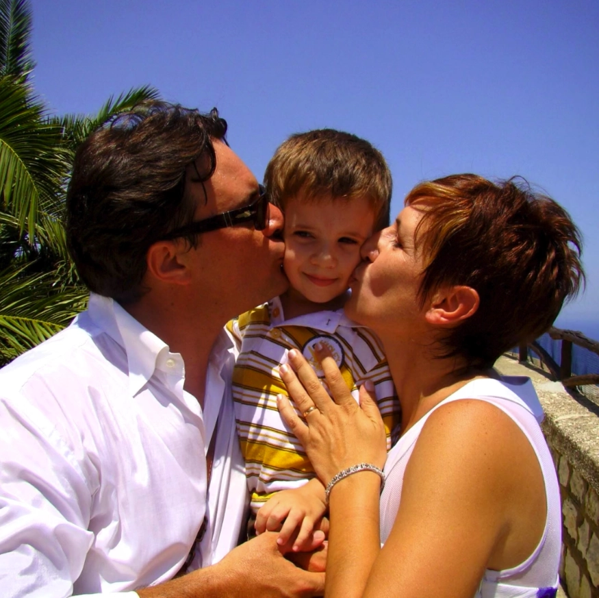 padre e madre che danno un bacio sulle guance del figlio contemporanemamente